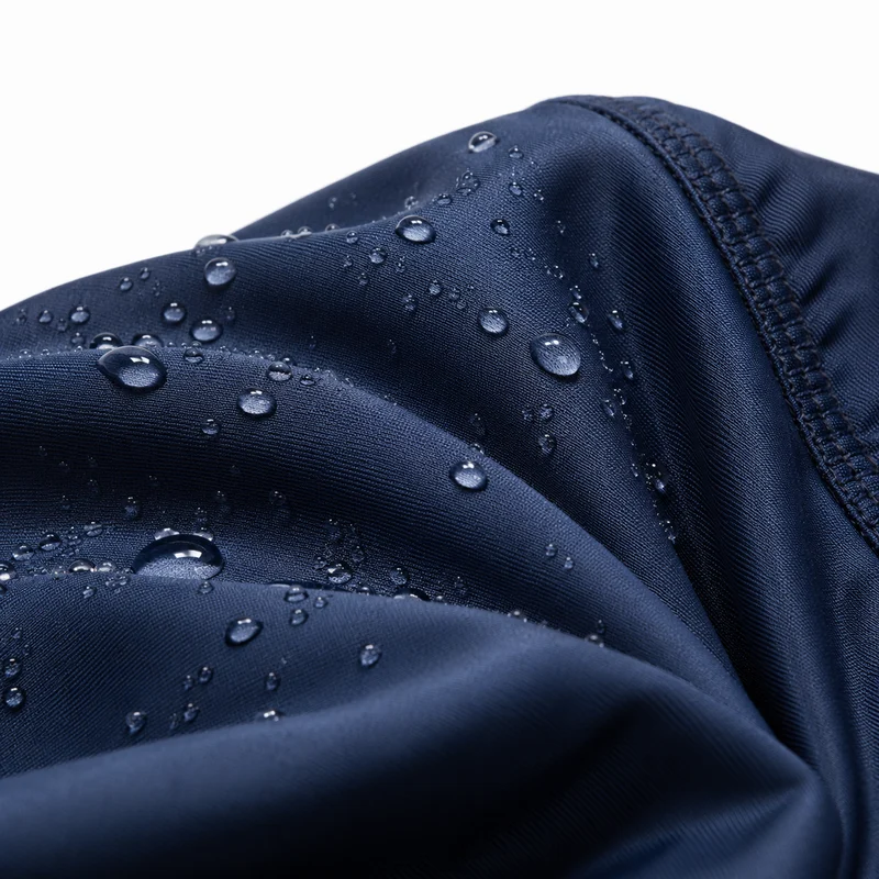 Détail tissu burkini sport natation — texture polyester élasthanne UPF 50+ bleu marine — étiquette certification, fond blanc